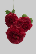 Three deep red artificial peony-style flowers with green leaves and stems, arranged on a plain white background.